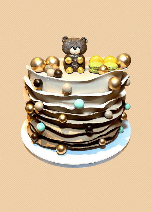 A custom baby shower cake with a bear topping.